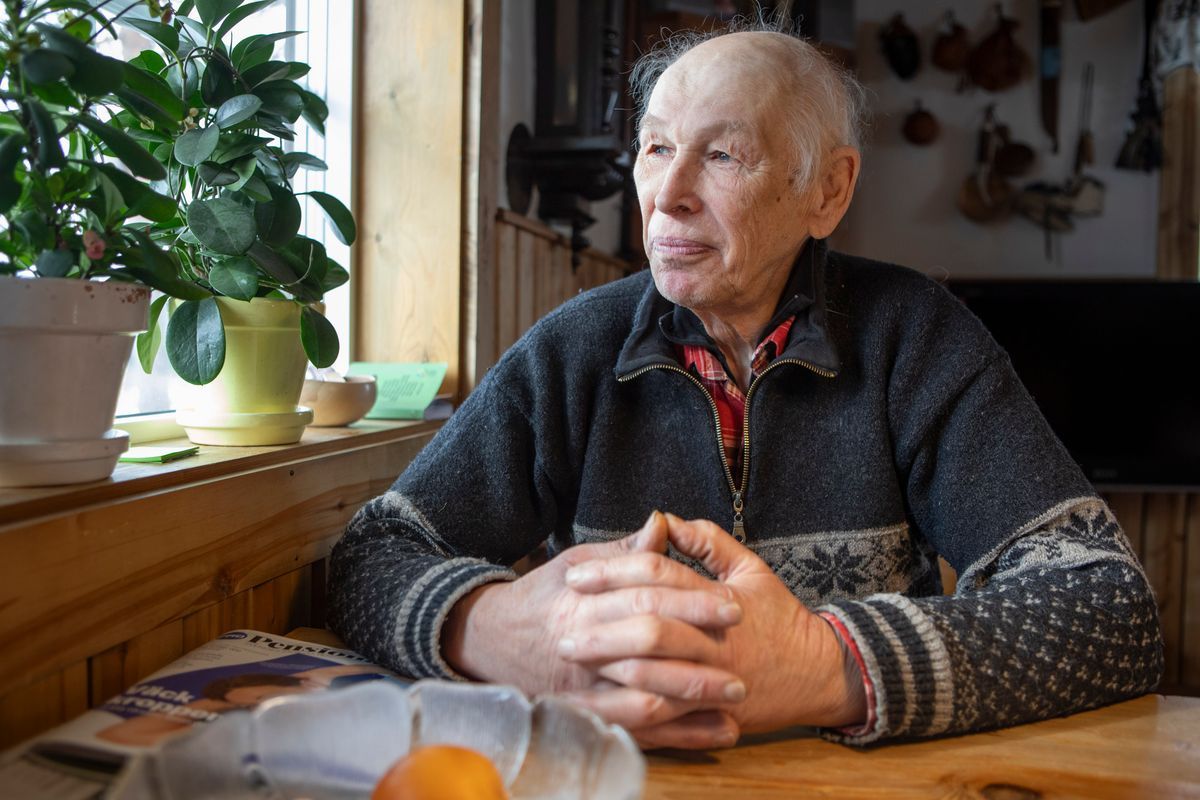 Äldre man sitter vid ett köksbord och tittar ut genom fönstret
