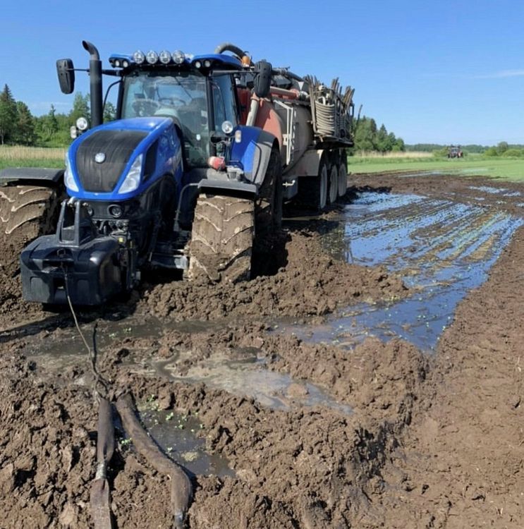 Traktor som fastnat på lerig åker.
